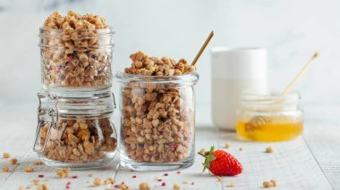 Farklı cam kavanozlarda ev yapımı granola ve taze çilek ve bal ile pankart. Hızlı bir kahvaltı, sağlıklı bir diyet..