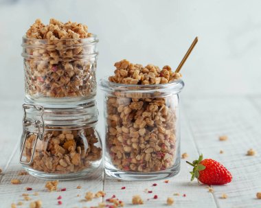 Farklı cam kavanozlarda taze çilekli ev yapımı granola. Hızlı bir kahvaltı, sağlıklı bir diyet..