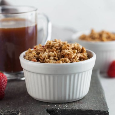 Beyaz kâse içinde ev yapımı granola ve bir fincan kahve. Sağlıklı kahvaltı kavramı.. 