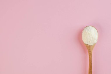  White collagen powder on a wooden spoon on a pink background. Skin care, rejuvenation. Copy space. High quality photo clipart