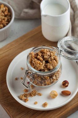 Tahta bir tahtanın üzerinde cam kavanozda fındıklı ev yapımı granola. Hızlı ve sağlıklı kahvaltı konsepti, vejetaryen kahvaltısı.