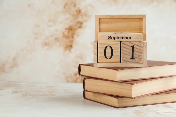 Wooden calendar September 1 on a stack of books. Concept for Knowledge Day, beginning of school year. Copy space. High quality photo
