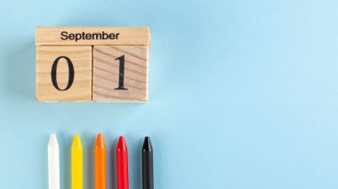 Tahta 1 Eylül takvimli pankart, mavi arka planda renkli kalemler. Uzayı kopyala Okul yılının başlangıcı