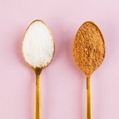 Hindistan cevizi ve saf beyaz şeker, pembe arka planda altın kaşıklarla. Minimalizm. Sağlıklı beslenme kavramı. Yüksek kalite fotoğraf.