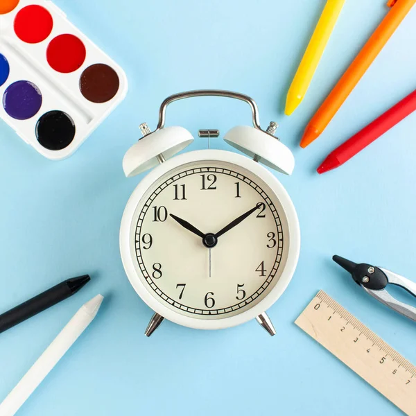 Reloj Despertador Blanco Sobre Fondo Azul Rodeado Bolígrafos Colores Otros — Foto de Stock