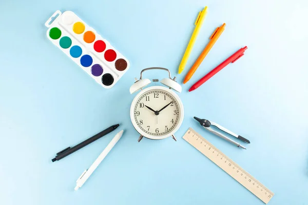 Reloj Despertador Blanco Sobre Fondo Azul Rodeado Bolígrafos Colores Otros — Foto de Stock