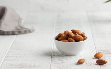 Hafif ahşap arka planda bir kasede badem. Sağlıklı atıştırmalıklar, vejetaryenler için yemek. Uzayı kopyala Yüksek kalite fotoğraf