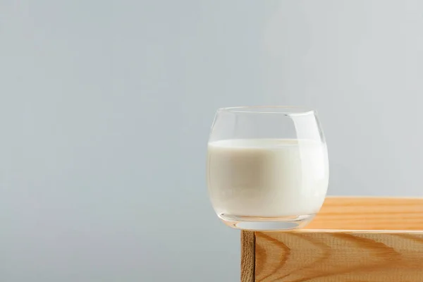A glass of milk on a light background on a wooden box. The concept of farm dairy products, the use of milk. Copy space. Horizontal food photo.