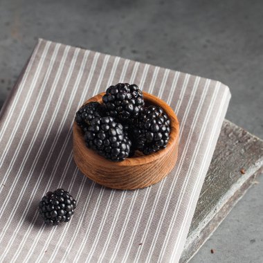 Gri arka planda tahta bir tabakta sulu olgun böğürtlenler. Koyu renk yemek fotoğrafı. Uzayı kopyala Yüksek kalite fotoğraf