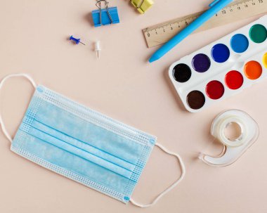 Koronavirüs salgınında sosyal mesafe ve eğitim kavramı. Yeni okul ve bilgi günü. Koruyucu maske ve bir kırtasiye seti. Yüksek kalite fotoğraf