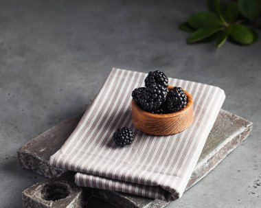 Gri arka planda tahta bir tabakta sulu olgun böğürtlenler. Koyu renk yemek fotoğrafı. Uzayı kopyala Yüksek kalite fotoğraf