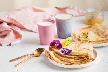 Çiçekler ve kahve fincanlarıyla süslenmiş tabakta nefis krepler. Kahvaltı kavramı, tatlı, tarif, Fransız mutfağı, Maslenitsa. Yüksek kalite fotoğraf