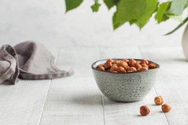 Beyaz ahşap arka planda gri bir kasede bir avuç fındık. Sağlıklı atıştırmalıklar. Kaçık. Uzayı kopyala Yüksek kalite fotoğraf