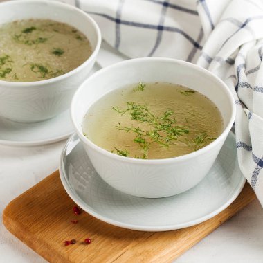 Ahşap arka planda beyaz bir kasede ev yapımı tavuk suyu çorbası. Sağlıklı beslenme kavramı. Uzayı kopyala Yüksek kalite fotoğraf