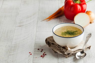 Ev yapımı et suyu peçetenin üzerinde beyaz bir kâse ve ahşap arka planda taze sebzeler. Sağlıklı beslenme kavramı. Uzayı kopyala Yüksek kalite fotoğraf