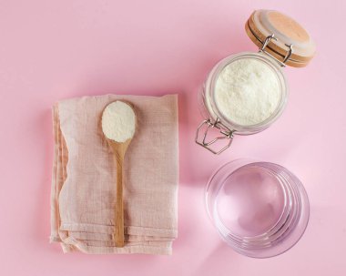 Pembe arka planda tahta kaşıkta beyaz kolajen tozu, bir bardak su. Cilt bakımı, gençleştirme. Uzayı kopyala Yüksek kalite fotoğraf