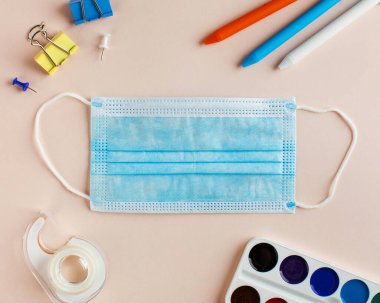 Koronavirüs salgınında sosyal mesafe ve eğitim kavramı. Yeni okul ve bilgi günü. Koruyucu maske ve bir kırtasiye seti. Yüksek kalite fotoğraf