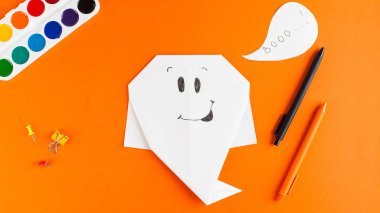 Turuncu arkaplandaki kağıttan hayalet afişi. Cadılar Bayramı konsepti, el sanatları..