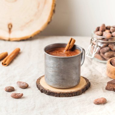 Masa örtüsünde tarçın çubuğu olan metal bardakta sıcak çikolata. Uzayı kopyala Yüksek kalite fotoğraf