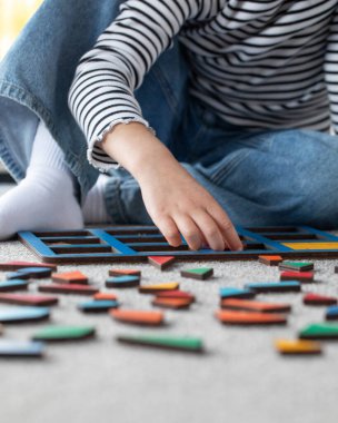 Çocuk halıda renkli geometrik bulmacalarla yaratıcı öğrenme ile meşgul. Çocuk gelişimi için eko oyuncaklar.