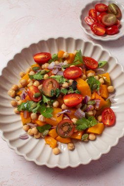 Taze nohut ve domatesli balkabağı salatası ve sağlıklı beslenmek için bitkiler. Sonbahar salatası. Sağlıklı ve vejetaryen yemeği kavramı.