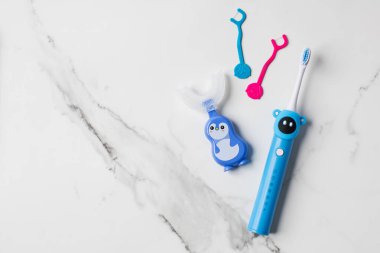 Çocuklar için tatlı ağız bakım aksesuarları ve sağlıklı diş hijyeni. Ultrasonik elektrikli diş fırçası, U şeklinde silikon diş fırçası ve diş ipiyle çocuk ağız sağlığı kiti. Ağız sağlığı konsepti. Anlaşıldı.