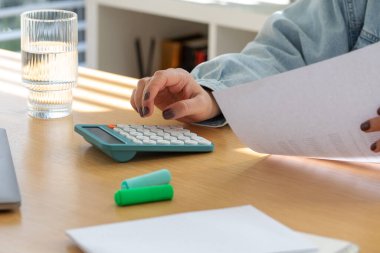 Hesap makinesi kullanan ve mali planlama için masa başında kağıt tutan biri. Aile bütçesi planlaması, maliyet hesaplaması ve mali yönetim. Aile bütçesi kavramı, kontrol masrafları