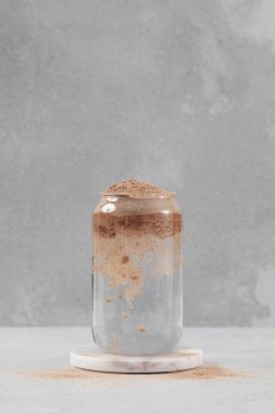 Çikolata proteini bir bardak suya düşer. Spor beslenme konsepti kas büyümesi için proteindir..