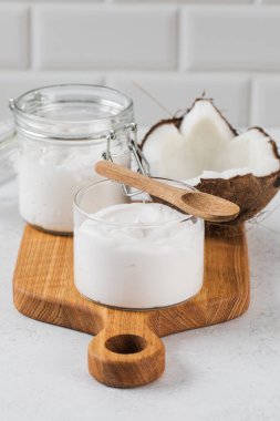 Ahşap tahtada kremalı hindistan cevizli yoğurt ve mutfak düzeninde kavanoz. Vejetaryen yoğurt kavramı