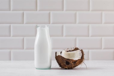Cam şişede taze hindistan cevizi sütü ve yarım hindistan cevizi. Vejetaryen sağlıklı süt kavramı