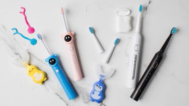 Yetişkinler ve çocuklar için ağız temizliği için farklı aksesuarlar. Aile için ultrasonik diş fırçası ve diş ipi. Ağız temizliği kavramı. 