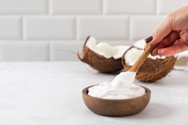 Tahta kaşık ve hindistan cevizli tahtadan bir kasede taze hindistan cevizli yoğurt. Vejetaryen yoğurt kavramı, laktozsuz. Boşluğu kopyala