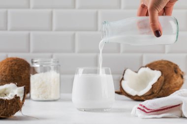 Taze hindistan cevizi sütü mutfak tezgahının üzerine dökülüyor. İçinde hindistan cevizi ve süt şişesi var. Alternatif, bitki sütü