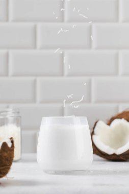 Dilimlenmiş hindistan cevizi arkaplanlı ve beyaz fayanslı taze hindistan cevizi sütü. Ücretsiz laktoz kavramı