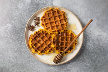 Tabağında yıldız anasonlu balkabağı gözlemeleri olan lezzetli ballı waffle. Sonbahar tarifleri kavramı.