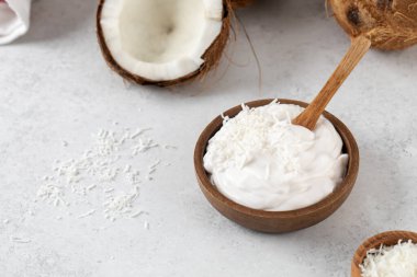 Tahta kaşık ve hindistan cevizli tahtadan bir kasede taze hindistan cevizli yoğurt. Vejetaryen yoğurt kavramı, laktozsuz..