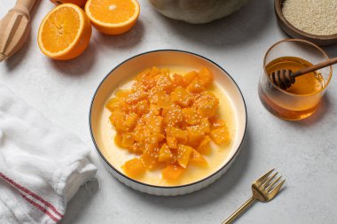 İçinde dilimlenmiş balkabağı, bal ve portakal suyu olan sağlıklı bir tatlı. Sağlıklı balkabağı yemeği konsepti.