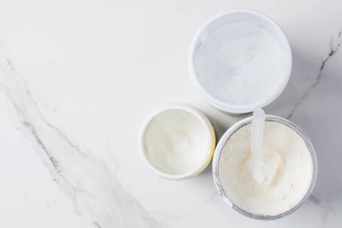 Beslenme ve zindelik için beyaz mermer zemin üzerine çeşitli protein tozu ve destek kepçeleri. Boşluğu kopyala