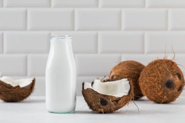 Cam şişede taze hindistan cevizi sütü ve yarım hindistan cevizi. Vejetaryen sağlıklı süt kavramı