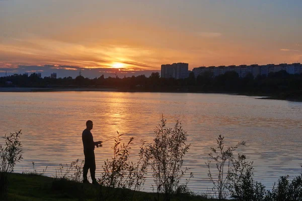 Pescatore sulla riva del fiume contro il cielo tramonto . — Foto Stock