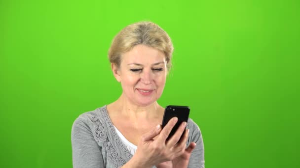 女性は、彼女の電話でテキスト メッセージを書き込みます。緑色の画面 — ストック動画