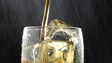 İçecek bir bardak buz içine dökülen ve su damla damla. Siyah arka plan. Yakın çekim