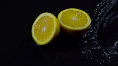 Yarım portakal ile su siyah zemin fışkırmaları. Ağır çekim