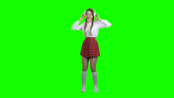 ヘッドホンで音楽を聴いている女の子。緑色の画面 — ストック動画