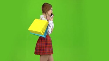 Kız ellerini ve telefon görüşmeleri paketlerinde adımlara. Yeşil ekran. Yan görünüm