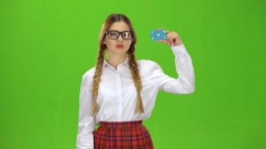 Gözlüklü kız öğrenci aşağı bir parmağını gösterir. Yeşil ekran