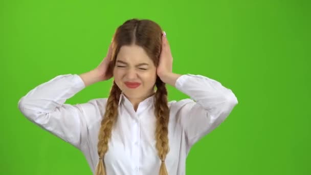 Школярка закриває вуха від шуму. Зелений екран — стокове відео