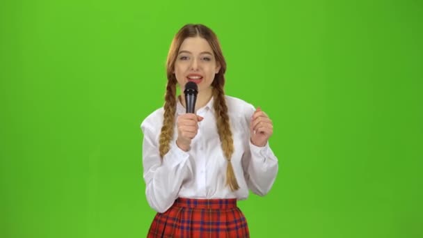 女の子は、マイクに向かって歌います。緑色の画面 — ストック動画