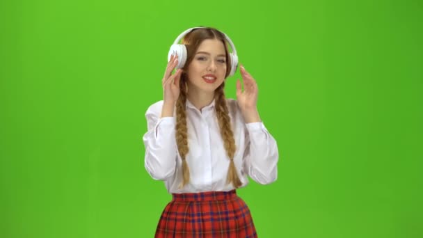 Dívka poslouchá hudbu ve sluchátkách. Zelená obrazovka — Stock video