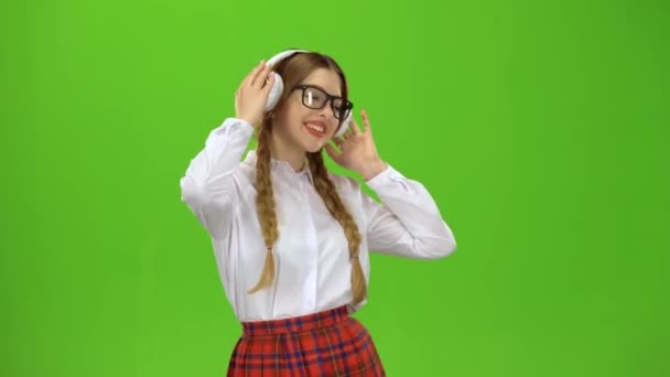Chica en gafas escucha música en los auriculares. Pantalla verde — Vídeos de Stock